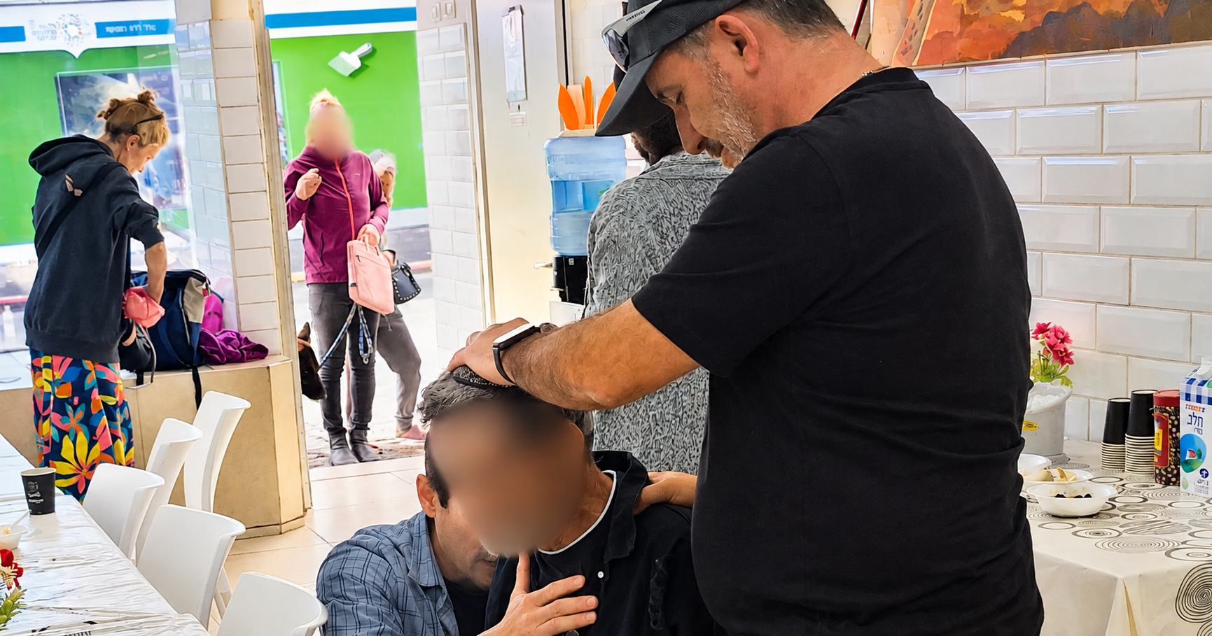 A volunteer prays with a person at the Tel Aviv Soup Kitchen; the person’s face is blurred.